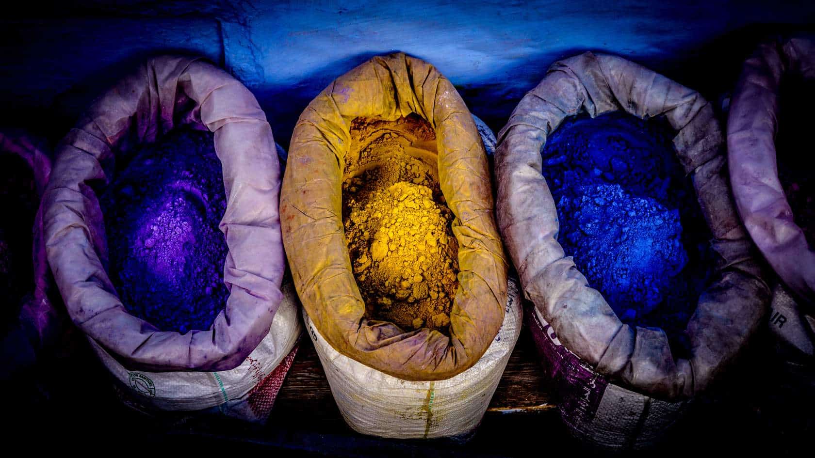 Bild av påsar med pulver i färgerna lila, gult och blått